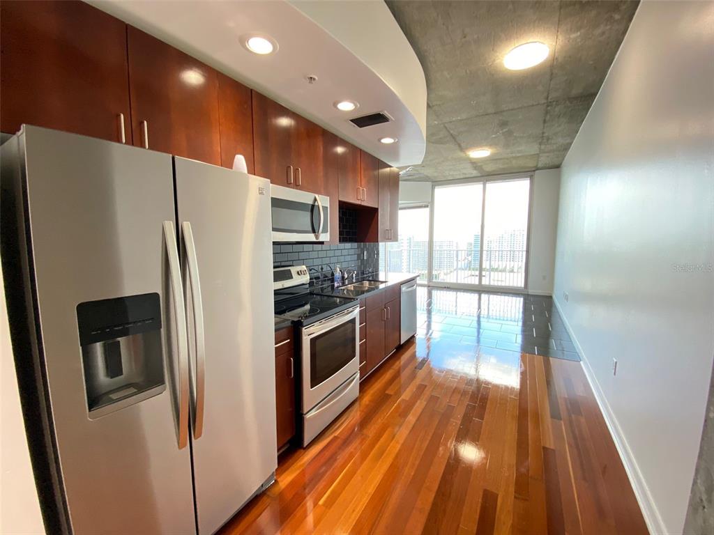 A modern kitchen features stainless steel appliances, dark wood cabinets, and hardwood flooring — 155 S COURT AVENUE UNIT 1603, ORLANDO, FL