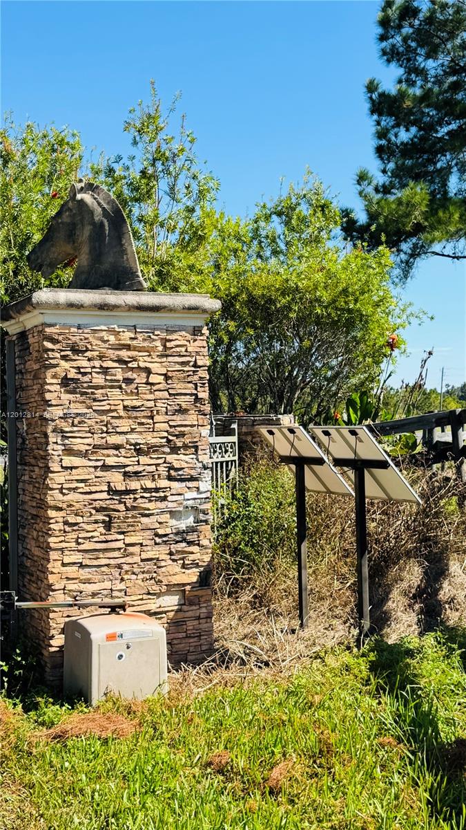 A stone pillar topped with a horse sculpture stands beside solar panels and a gate — 14500 N HWY 27, Ocala FL 34482, OCALA, FL