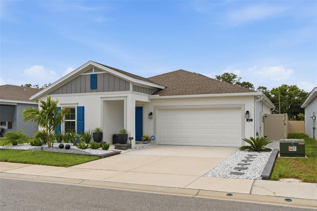A single-story house with a white stucco exterior, blue shutters, and a two-car garage — 412 ADAMS ALE PLACE, DAVENPORT, FL
