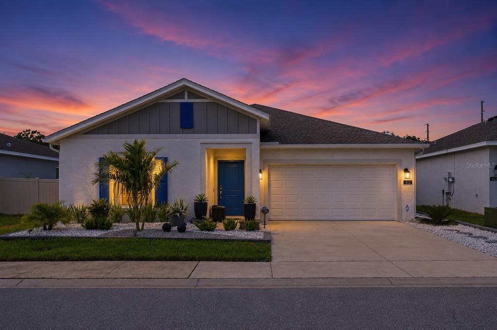 A single-story house with a blue front door, a two-car garage, and a landscaped yard — 412 ADAMS ALE PLACE, DAVENPORT, FL