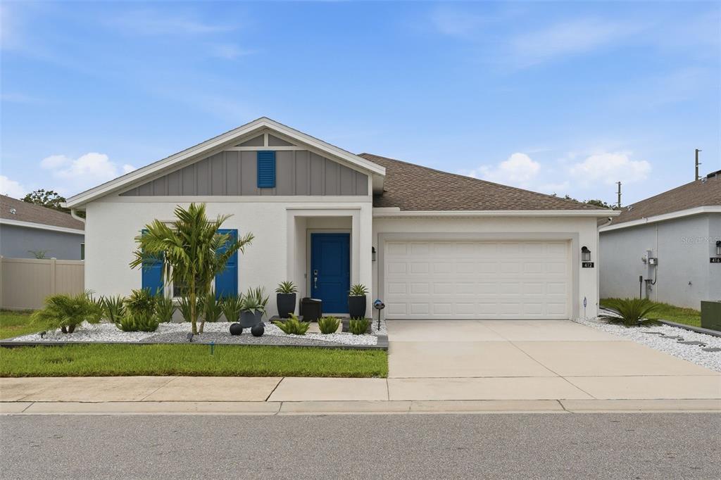 A single-story house with a white stucco exterior, blue shutters, and a two-car garage — 412 ADAMS ALE PLACE, DAVENPORT, FL