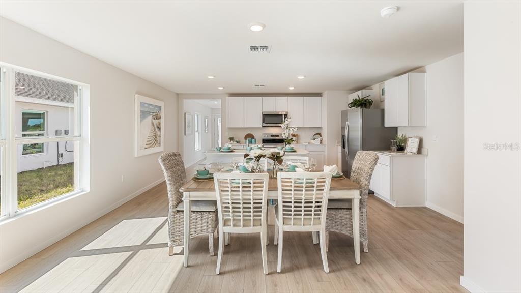 A dining area with a wooden table and chairs sits adjacent to a modern kitchen — 26229 SACRED LOTUS LANE, PUNTA GORDA, FL