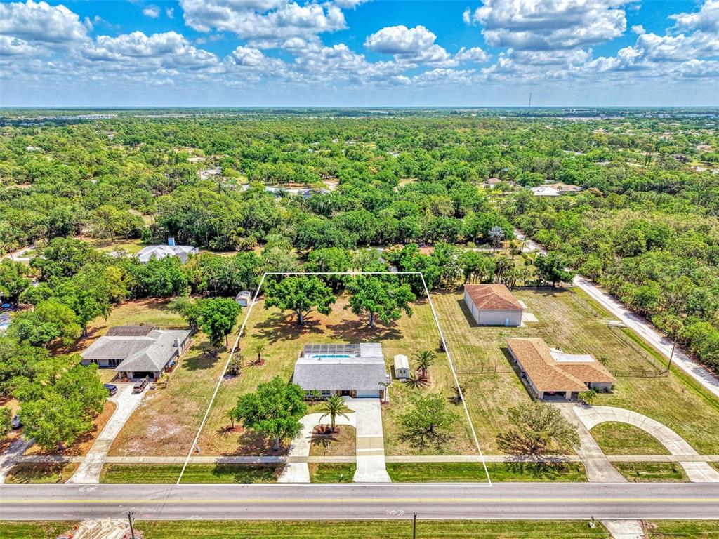 An aerial view shows a house with a pool and two detached buildings on land — 1620 MISSION VALLEY BOULEVARD, NOKOMIS, FL