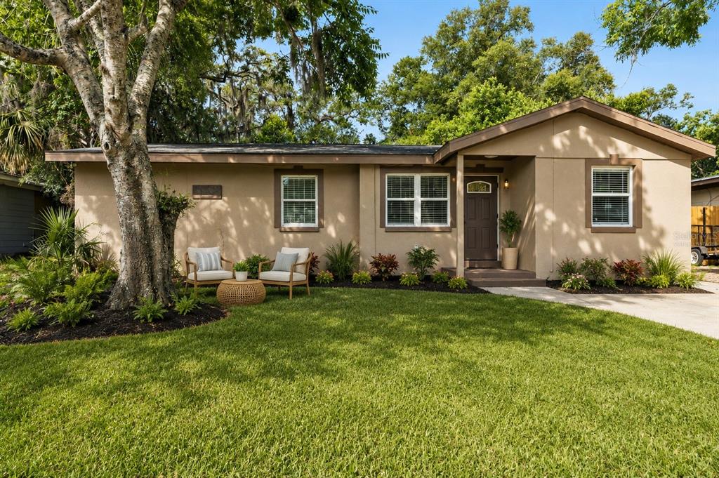 A single-story tan house with a front lawn, a large tree, and a small porch — 540 COLFAX DRIVE, DAYTONA BEACH, FL