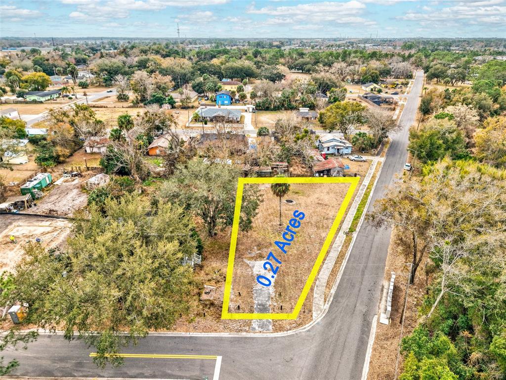 An aerial view shows a vacant, trapezoidal lot outlined in yellow on a corner street — MCKAY STREET, SANFORD, FL