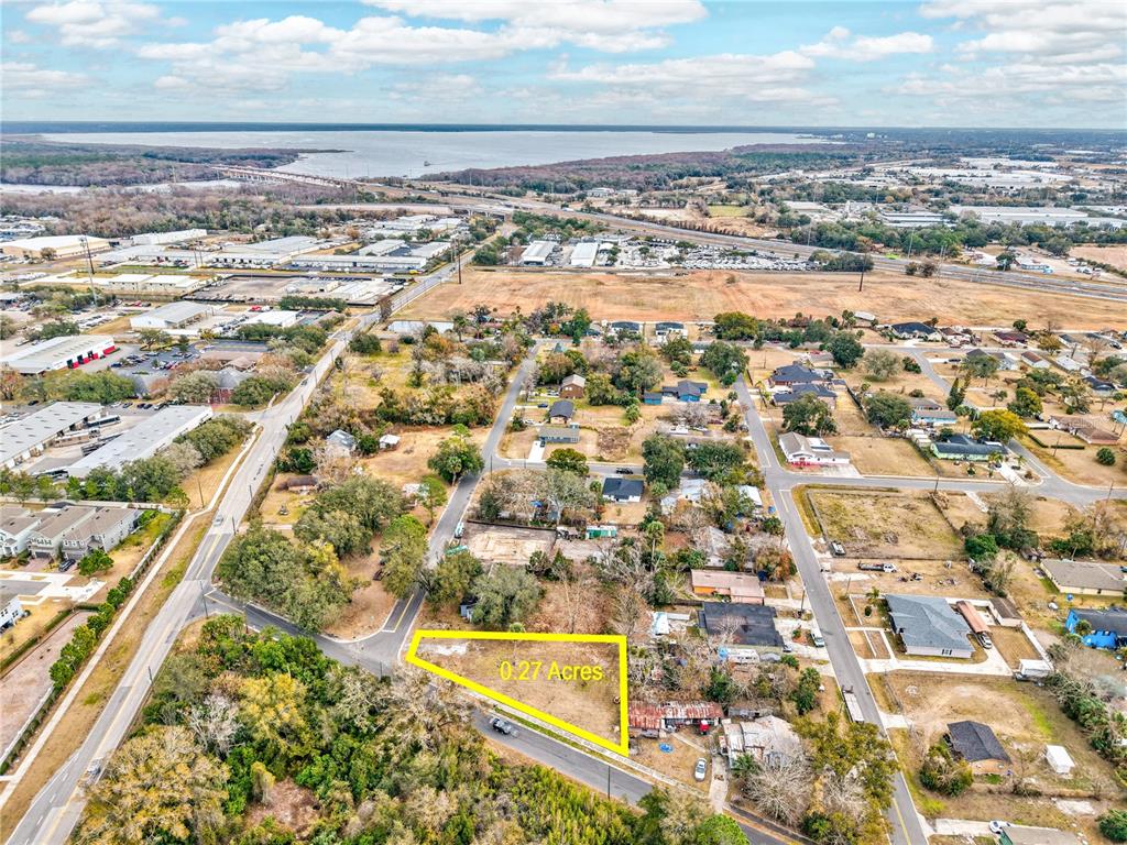 An aerial view shows a vacant, triangular-shaped lot highlighted in yellow within a residential neighborhood — MCKAY STREET, SANFORD, FL