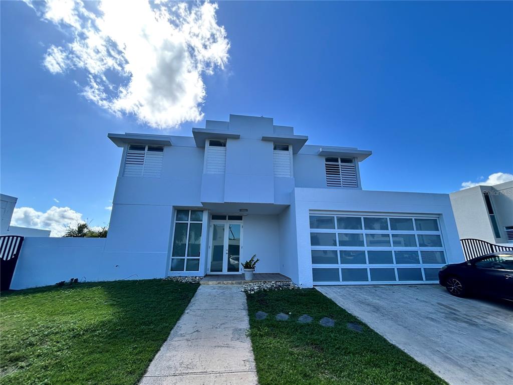 A two-story white house with a glass garage door and a front walkway — 345 CALLE TULIPAN, CAGUAS, PR