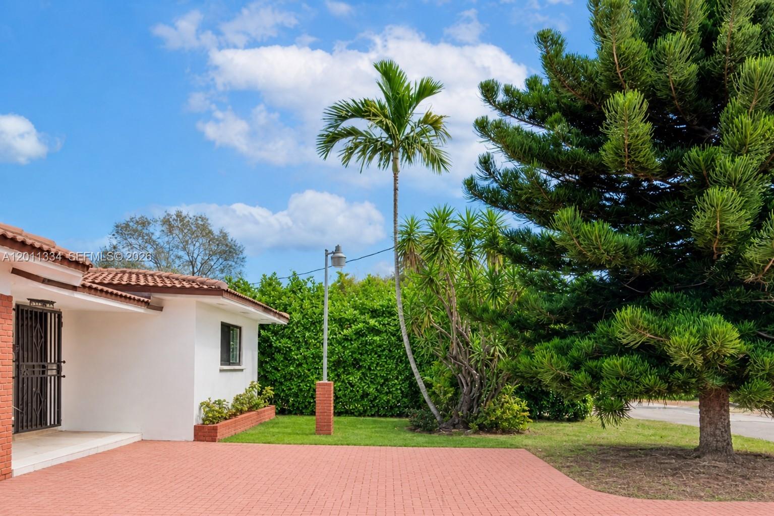A white house with a red brick driveway and a tall palm tree outside — 6385 SW 25th St, Miami FL 33155, MIAMI, FL