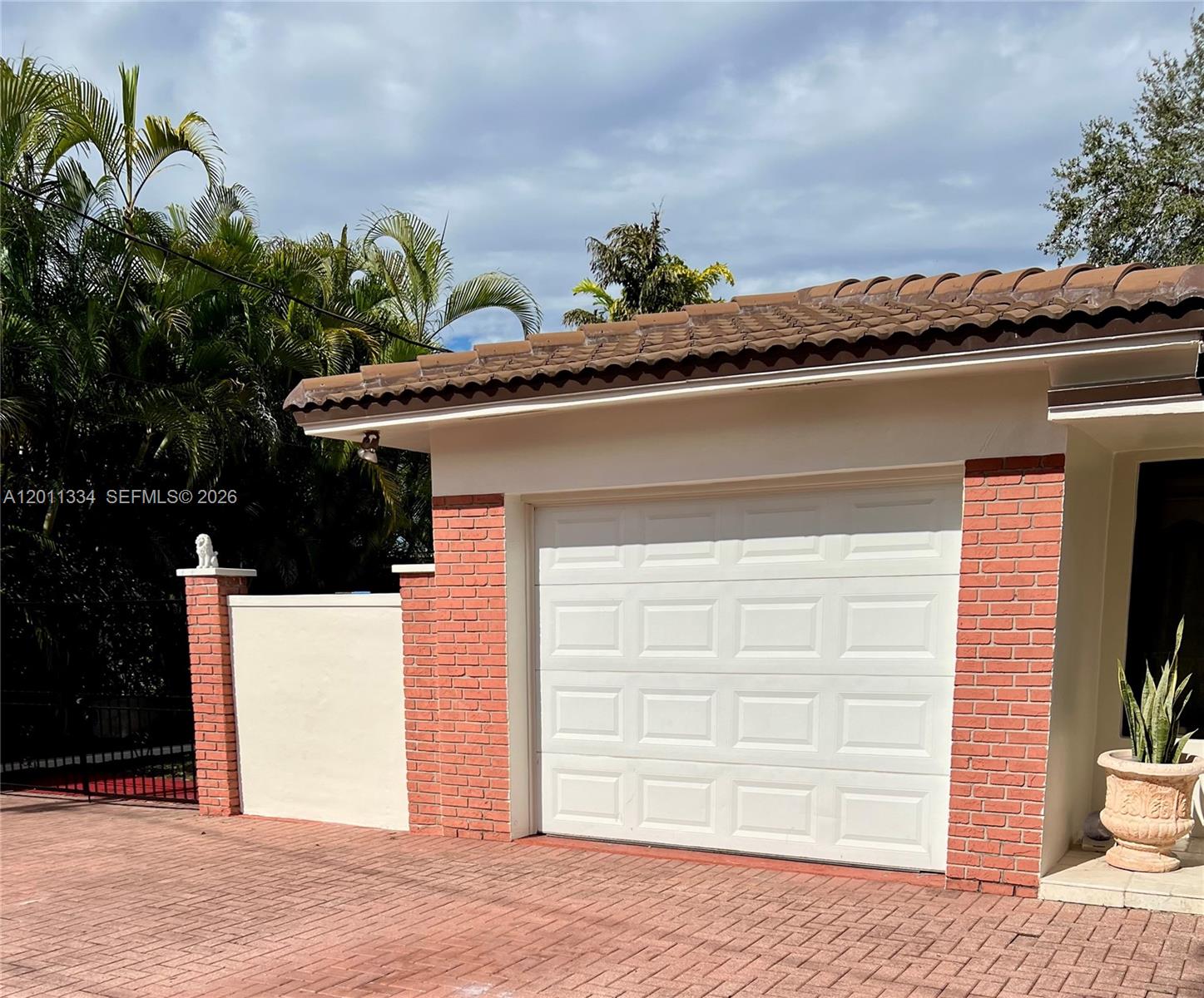 A white garage door is framed by red brick pillars on a paved driveway — 6385 SW 25th St, Miami FL 33155, MIAMI, FL