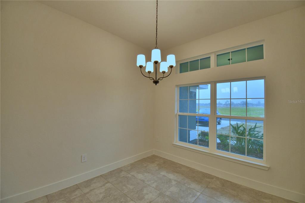 A dining area features tile flooring, a chandelier, and a large window with transom lights — 4611 CALAMINT LANE, AUBURNDALE, FL