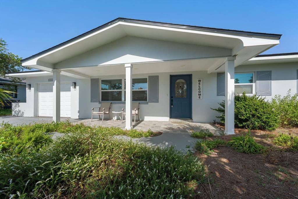 A single-story house with a white exterior, a covered porch, and a blue front door — 8879 111TH STREET, SEMINOLE, FL