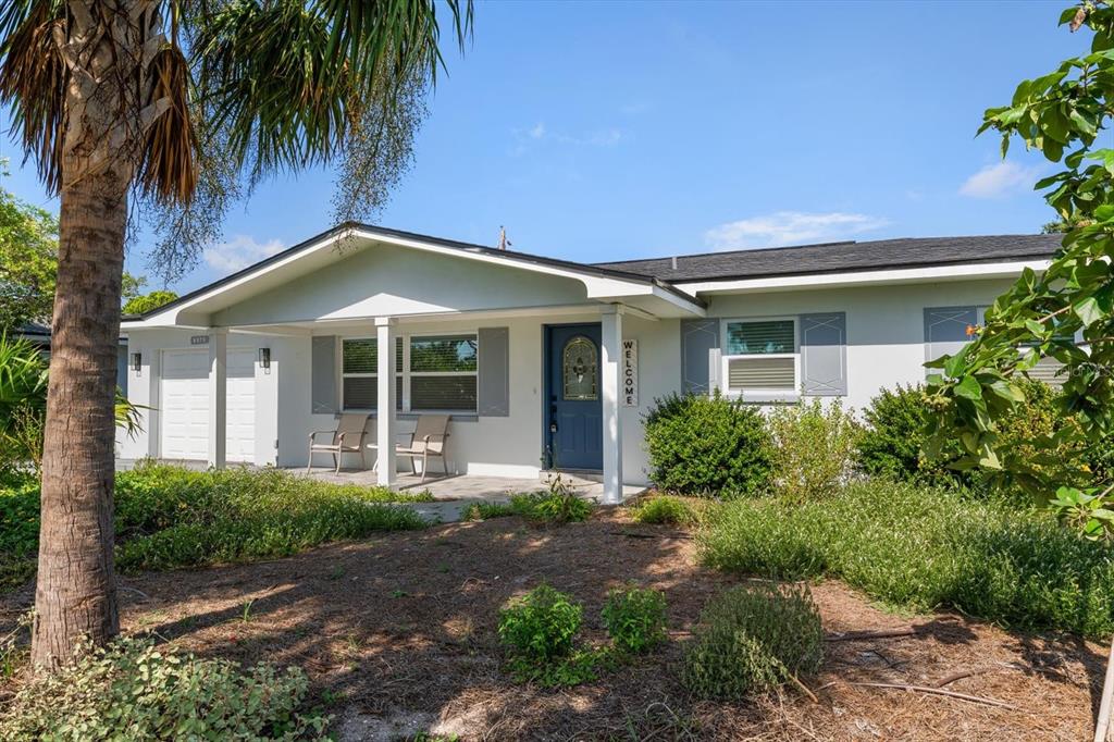 A single-story house with a blue front door, covered porch, and a palm tree — 8879 111TH STREET, SEMINOLE, FL