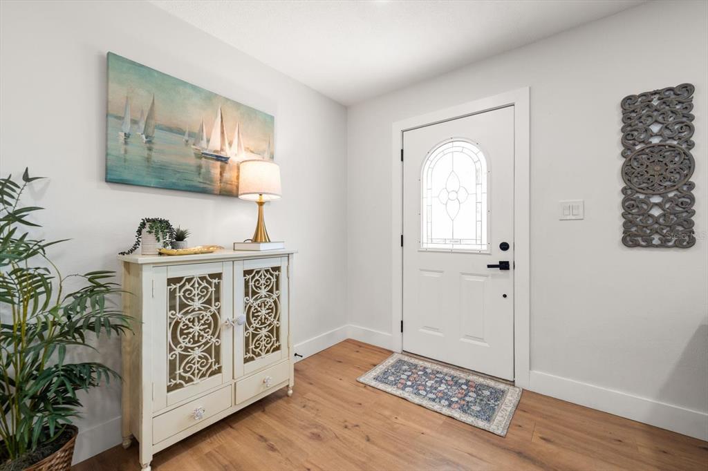 An entryway features a white cabinet, a sailboat painting, and a white front door — 8879 111TH STREET, SEMINOLE, FL