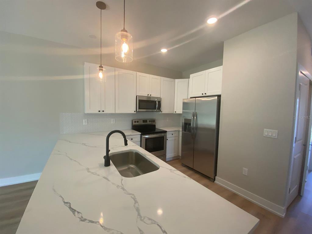 A modern kitchen features white cabinets, stainless steel appliances, and a large marble-patterned island — 9285 AGATE STREET, PORT CHARLOTTE, FL