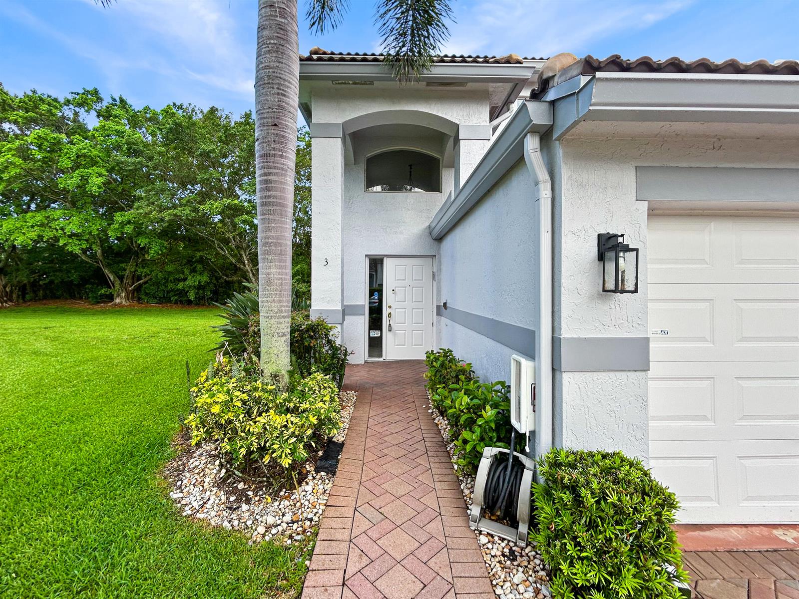 A paved walkway leads to the front entrance of a house with a palm tree — 7880 Laina Lane # 3, Boynton Beach FL 33437, BOYNTON BEACH, FL