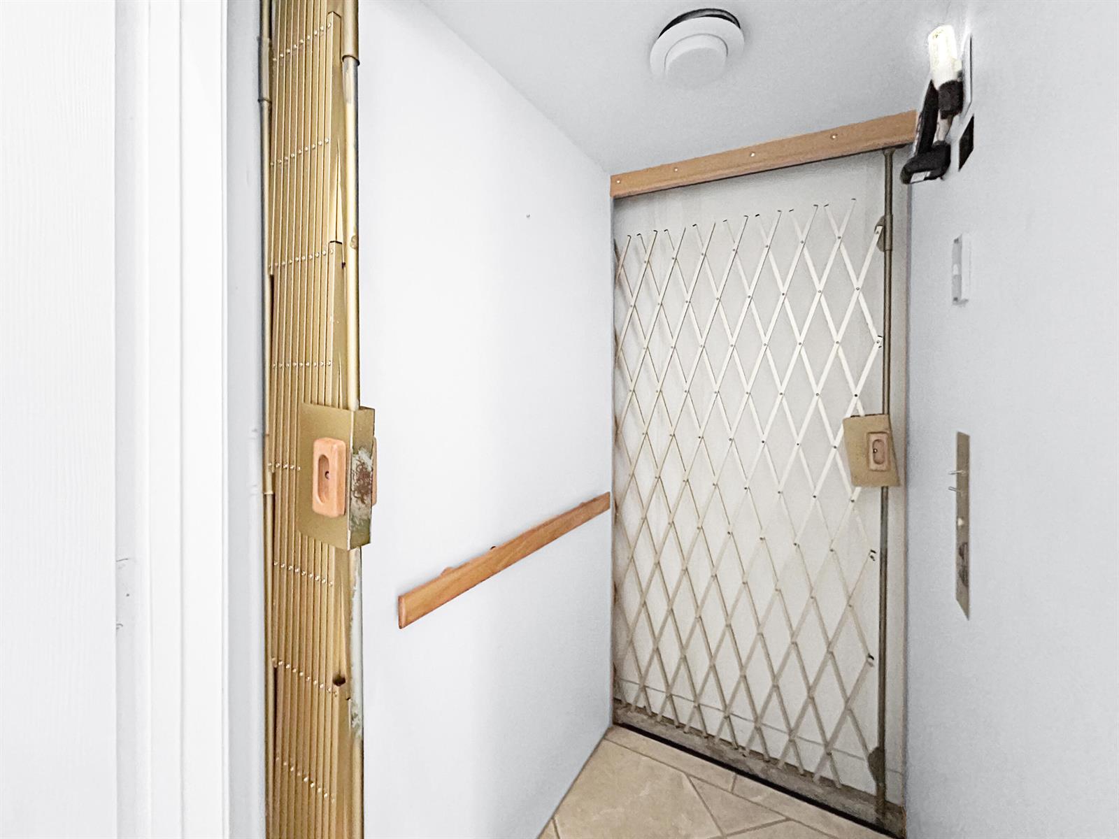 A narrow hallway features a gold-toned accordion security gate and a white metal scissor gate — 7880 Laina Lane # 3, Boynton Beach FL 33437, BOYNTON BEACH, FL