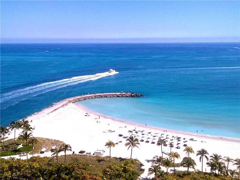 An aerial view of a white sand beach with a stone jetty and a boat — 10295 COLLINS AV # 1202, Bal Harbour FL 33154, BAL HARBOUR, FL