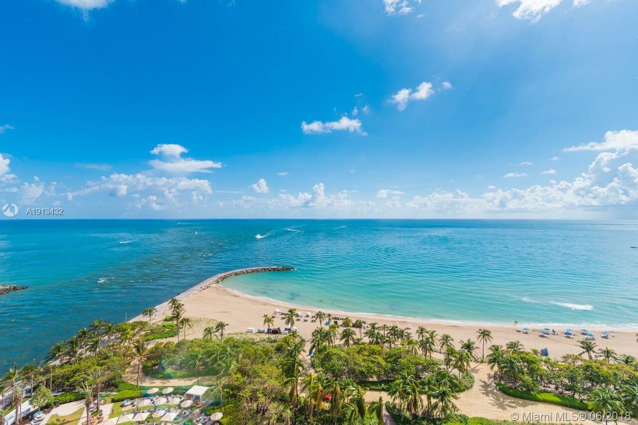 An aerial view of a sandy beach, palm trees, and a jetty extending into the ocean — 10295 COLLINS AV # 1202, Bal Harbour FL 33154, BAL HARBOUR, FL