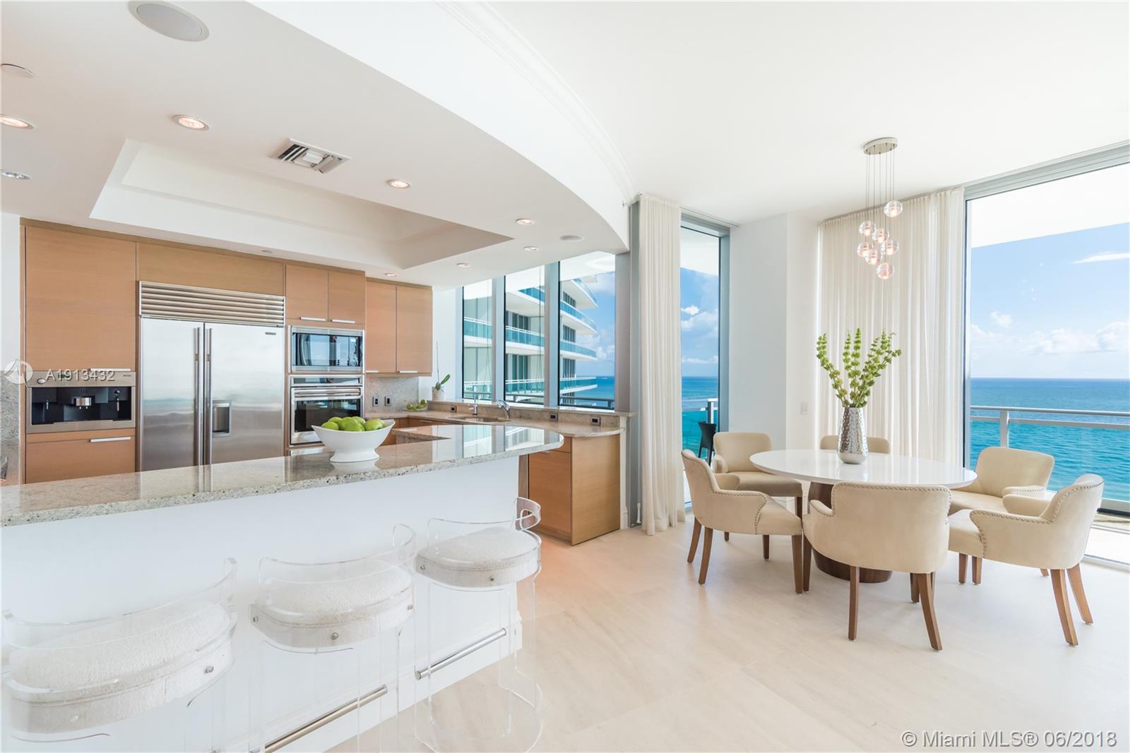 A modern kitchen and dining area feature light wood cabinetry, granite countertops, and ocean views — 10295 COLLINS AV # 1202, Bal Harbour FL 33154, BAL HARBOUR, FL