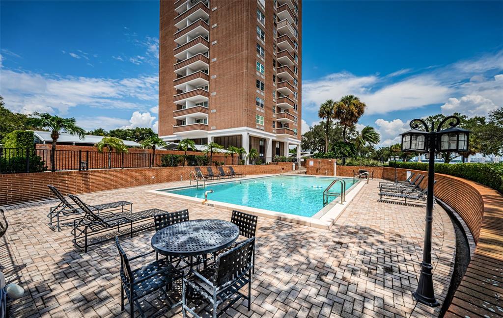 A brick high-rise building overlooks a rectangular swimming pool with a surrounding paved patio — 4015 BAYSHORE BOULEVARD UNIT 4C, TAMPA, FL