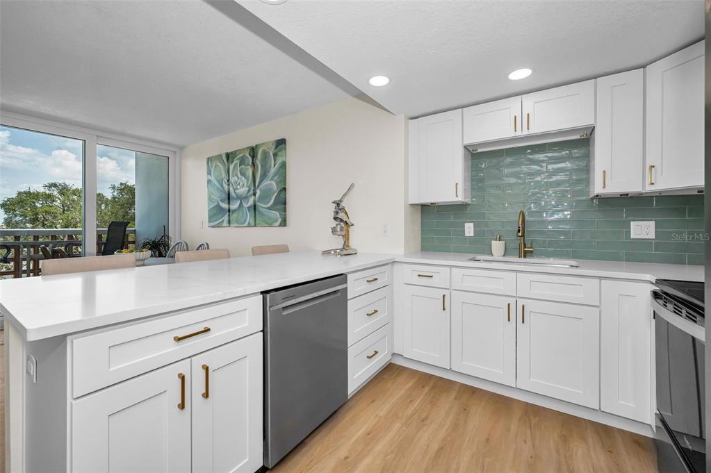 A modern kitchen features white cabinets, a light-colored countertop, and a teal subway tile backsplash — 4015 BAYSHORE BOULEVARD UNIT 4C, TAMPA, FL