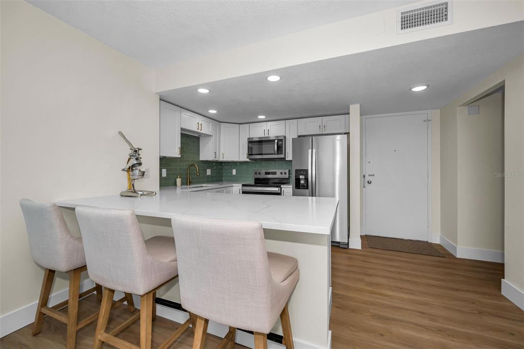 A modern kitchen features white cabinets, a quartz breakfast bar, and stainless steel appliances — 4015 BAYSHORE BOULEVARD UNIT 4C, TAMPA, FL