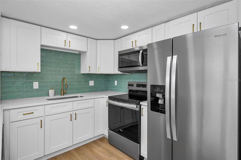 A kitchen features white cabinets, stainless steel appliances, and a green subway tile backsplash — 4015 BAYSHORE BOULEVARD UNIT 4C, TAMPA, FL