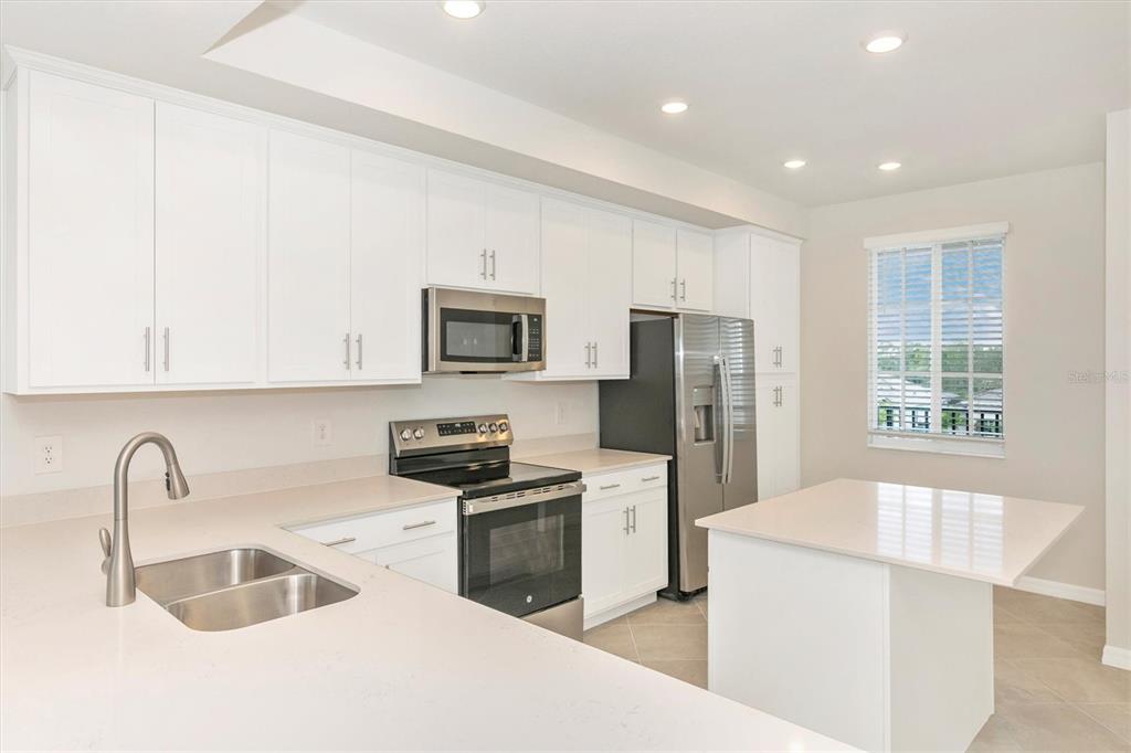 A kitchen with white cabinets, stainless steel appliances, a kitchen island, and light countertops — 12320 WELLEN GOLF STREET UNIT 305, VENICE, FL