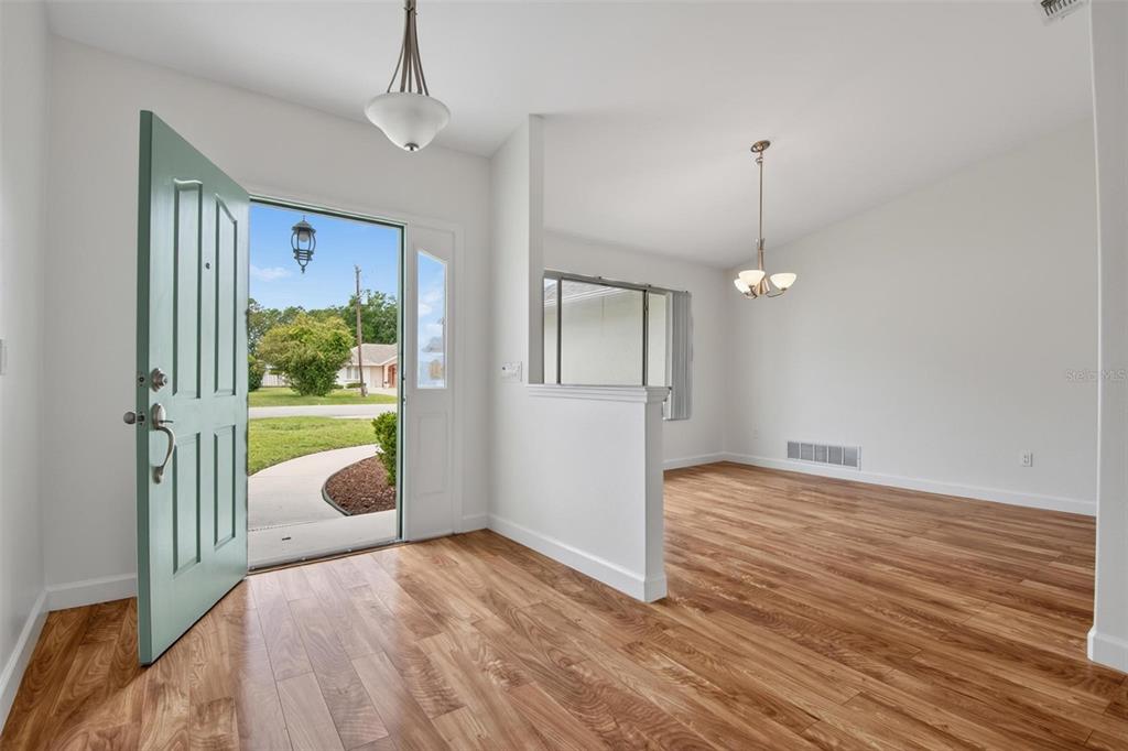 An entryway with wood-look flooring leads into a dining area with a half-wall partition — 231 WELLINGTON DRIVE, PALM COAST, FL