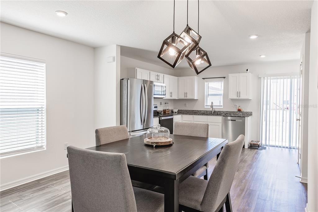 A dining area with a dark wood table sits adjacent to a white kitchen — 2234 MAJESTIC SPAN AVENUE, EAGLE LAKE, FL