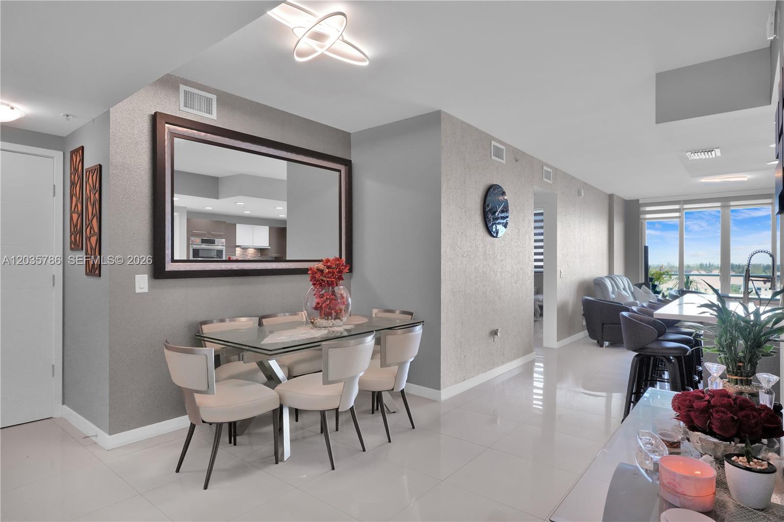 A dining area with a glass table, modern chairs, and a large wall mirror — 7751 NW 107th Ave # 701, Doral FL 33178, DORAL, FL