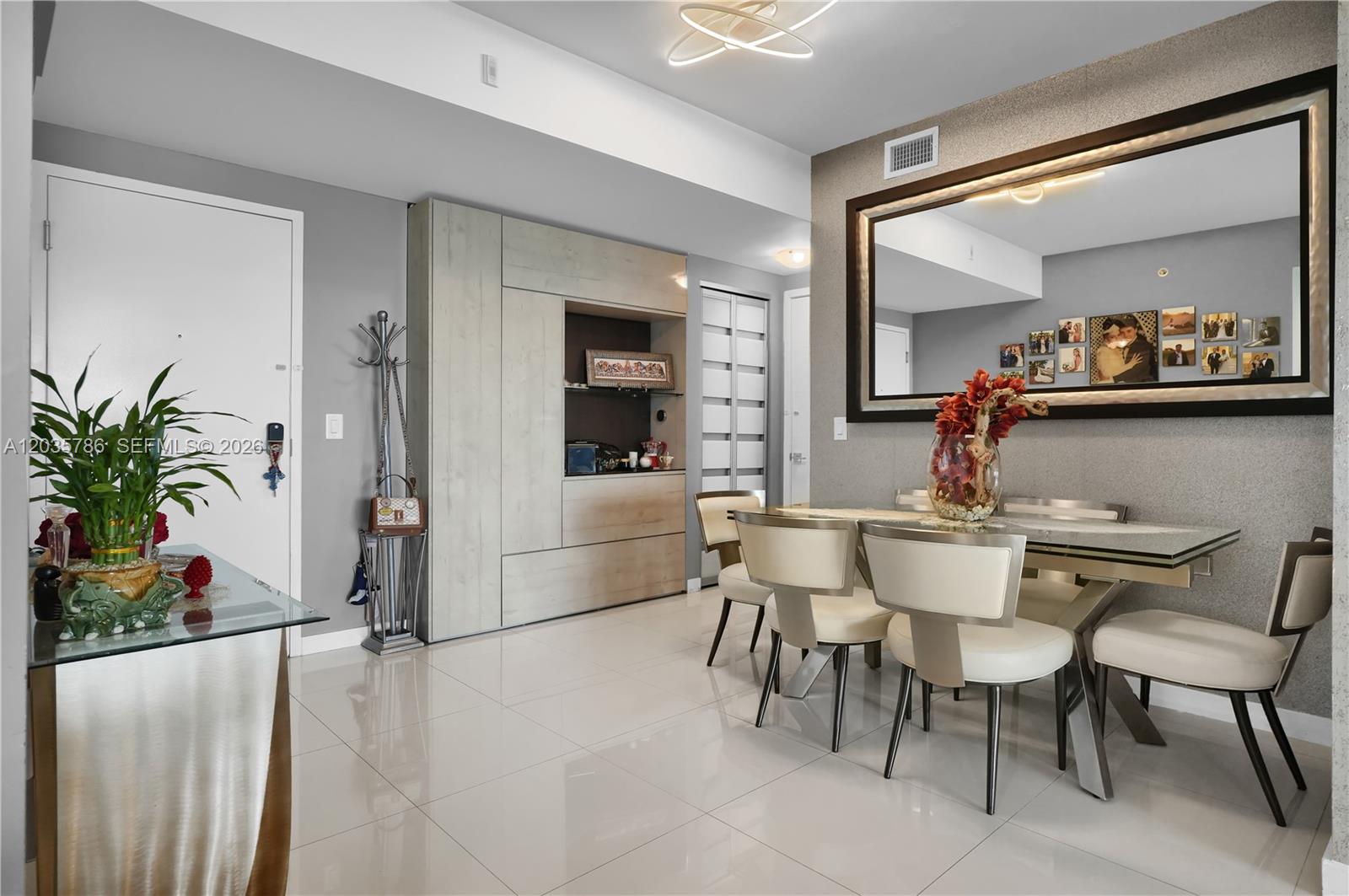 A dining room features a glass table, cream chairs, a large mirror, and light-colored tile — 7751 NW 107th Ave # 701, Doral FL 33178, DORAL, FL