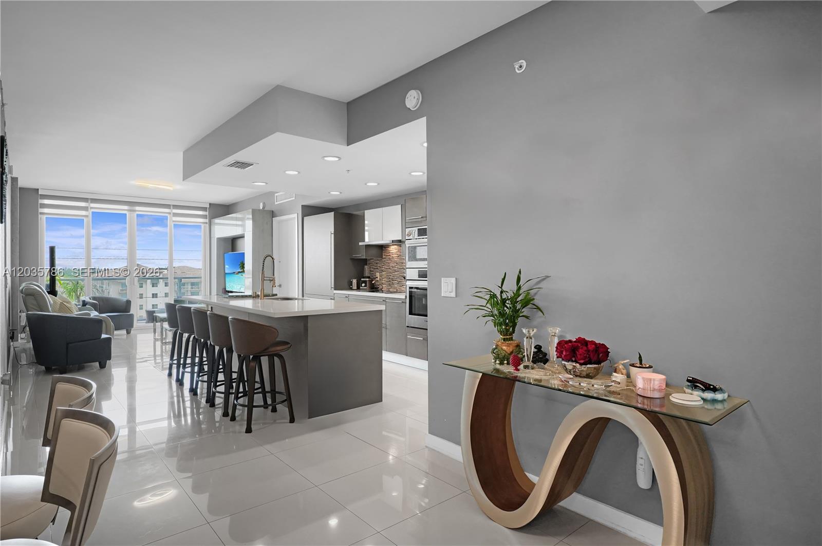 A modern open-concept kitchen and living area features a central island with bar seating — 7751 NW 107th Ave # 701, Doral FL 33178, DORAL, FL