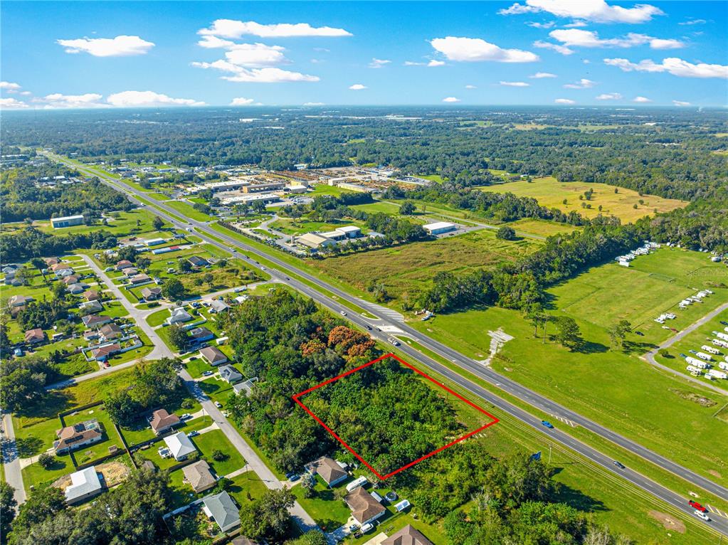An aerial view shows a rectangular wooded lot outlined in red next to a highway — 0 N US HWY 441, OCALA, FL