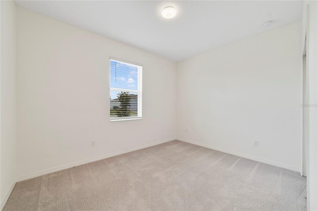 An empty bedroom features white walls, light gray carpeting, a single window, and a ceiling light — 662 FAIRVIEW AVENUE, HAINES CITY, FL