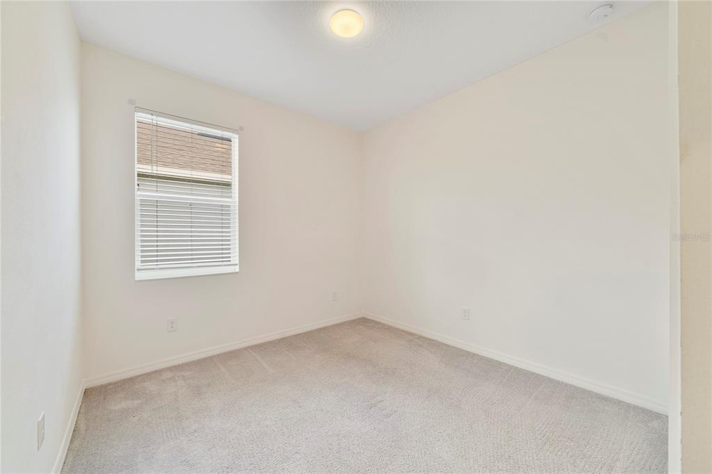 An empty bedroom with beige carpet, off-white walls, a single window, and a ceiling light — 662 FAIRVIEW AVENUE, HAINES CITY, FL
