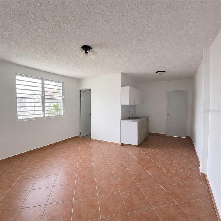 An open-concept room features white walls, tiled floors, a small kitchenette, and a window — 143 JARDINES DE COUNTRY CLUB Apt 2, CAROLINA, PR