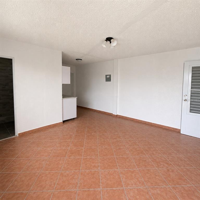 An interior view of a room with white walls, terracotta tile flooring, and a kitchen area — 143 JARDINES DE COUNTRY CLUB Apt 2, CAROLINA, PR