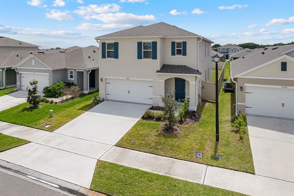 A two-story suburban house with a tan exterior, blue shutters, and a two-car garage — 3524 SUNGROVE CIRCLE, SANFORD, FL