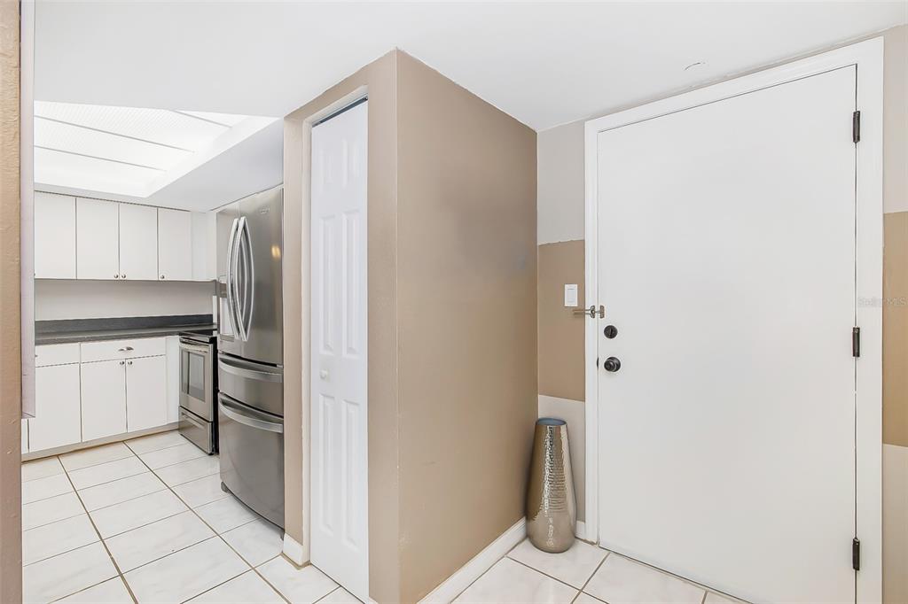 A kitchen with white cabinets and stainless steel appliances sits next to a white door — 51 ISLAND WAY UNIT 108, CLEARWATER BEACH, FL