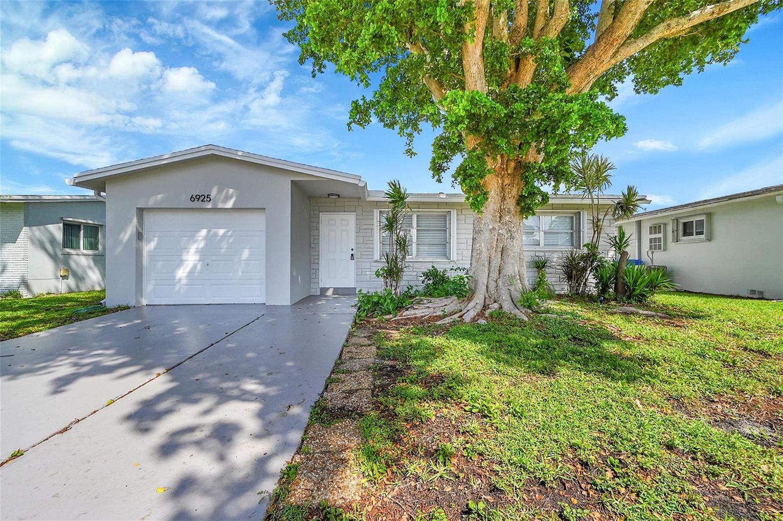 A single-story house with a gray exterior, a one-car garage, and a large front tree — 6925 NW 11th Street, Margate FL 33063, MARGATE, FL