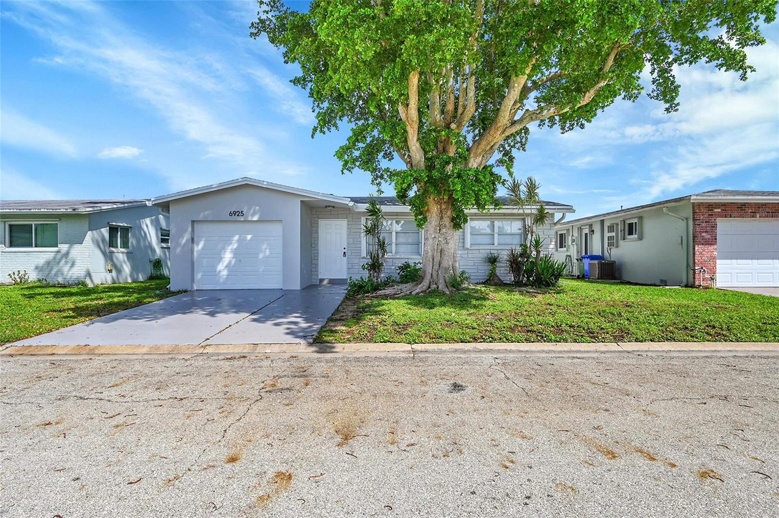 A single-story house with a white garage, gray exterior, and a large tree in front — 6925 NW 11th Street, Margate FL 33063, MARGATE, FL