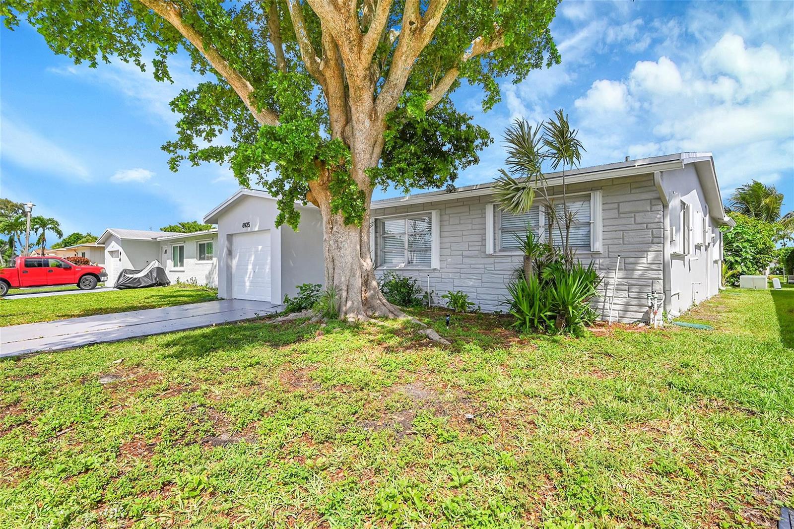 A single-story house with gray stone siding and a large tree in the front yard — 6925 NW 11th Street, Margate FL 33063, MARGATE, FL
