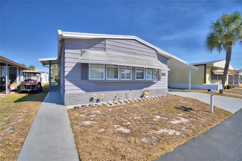 A light purple manufactured home with a metal awning over the front windows and carport — 4321 CHERRYWOOD STREET, WINTER HAVEN, FL