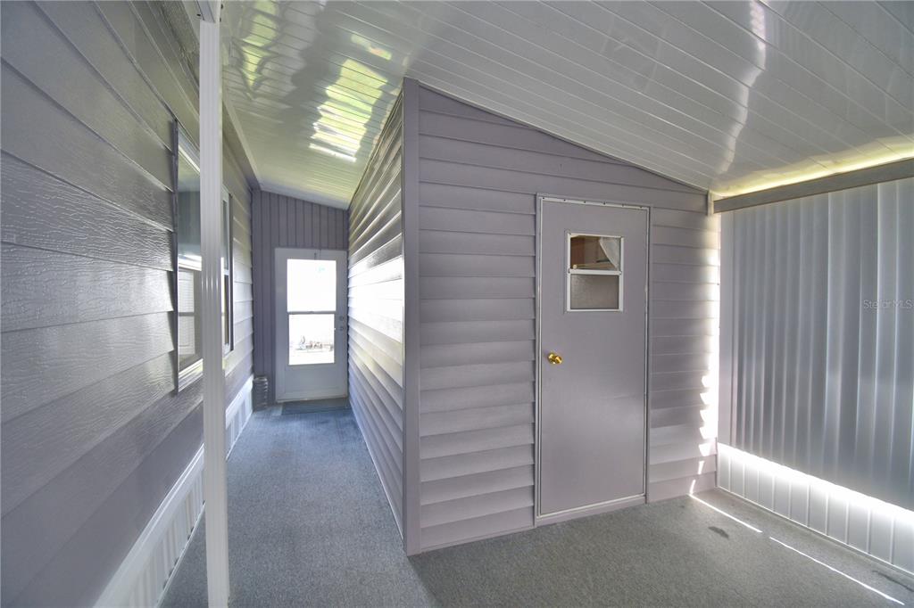 A covered outdoor patio features gray vinyl siding, a storage shed door, and carpeted flooring — 4321 CHERRYWOOD STREET, WINTER HAVEN, FL