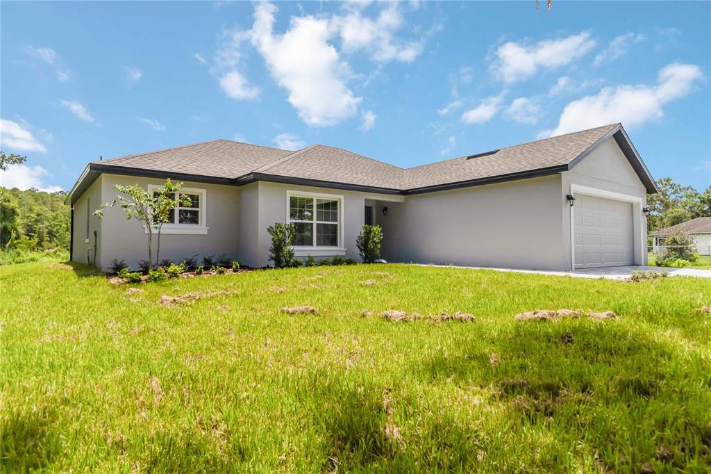 A single-story gray house with a two-car garage and a grassy front yard — 3525 RAMBLER AVENUE, ST CLOUD, FL