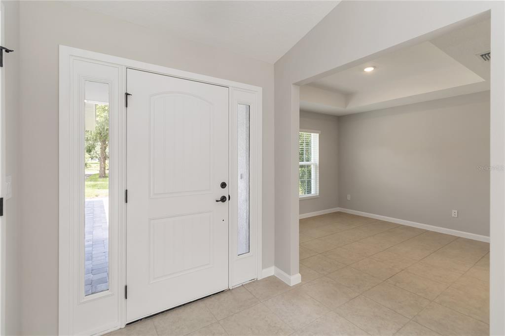 An entryway with a white front door and sidelights leads into a tiled room — 3525 RAMBLER AVENUE, ST CLOUD, FL