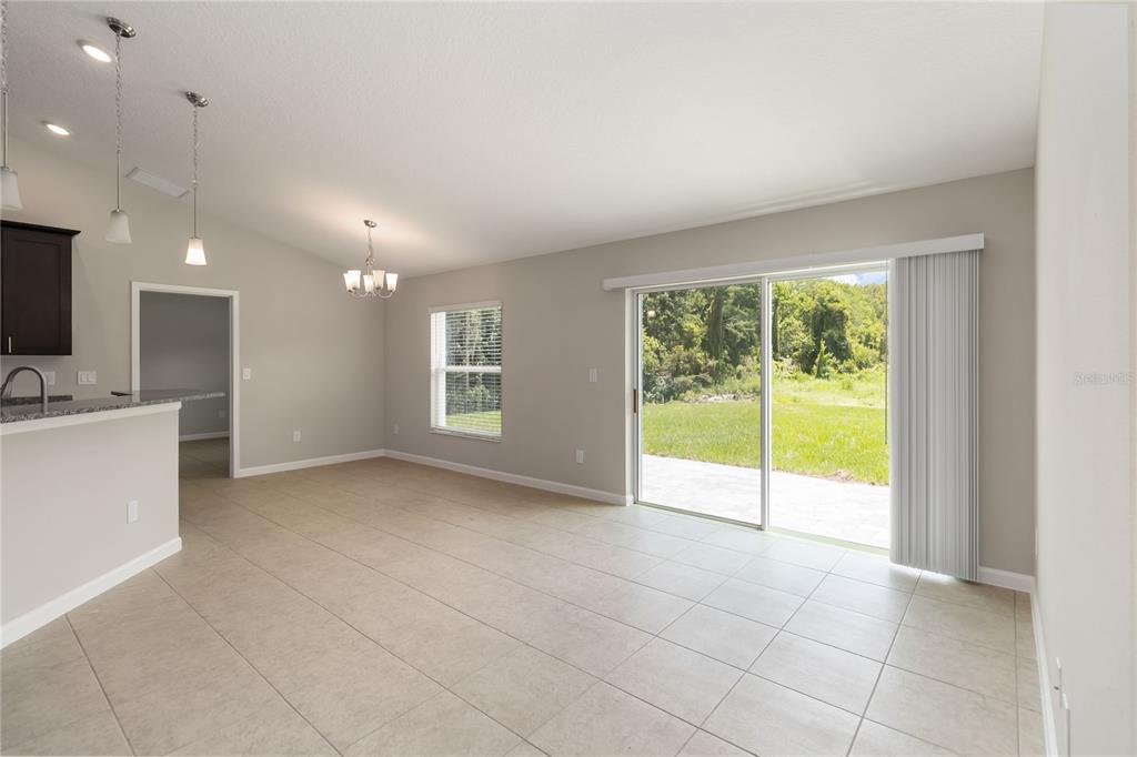 An open-concept dining area features tile flooring, a chandelier, and sliding glass doors to outdoors — 3525 RAMBLER AVENUE, ST CLOUD, FL