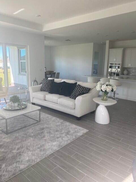 A living room with a white sofa, gray patterned rug, and an open-concept kitchen — 1121 Haywagon Trail, Loxahatchee FL 33470, LOXAHATCHEE, FL
