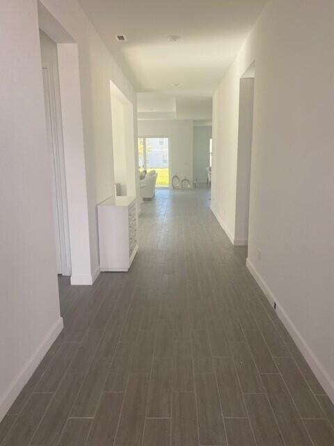 A long, narrow hallway features light gray wood-look tile flooring and white walls — 1121 Haywagon Trail, Loxahatchee FL 33470, LOXAHATCHEE, FL